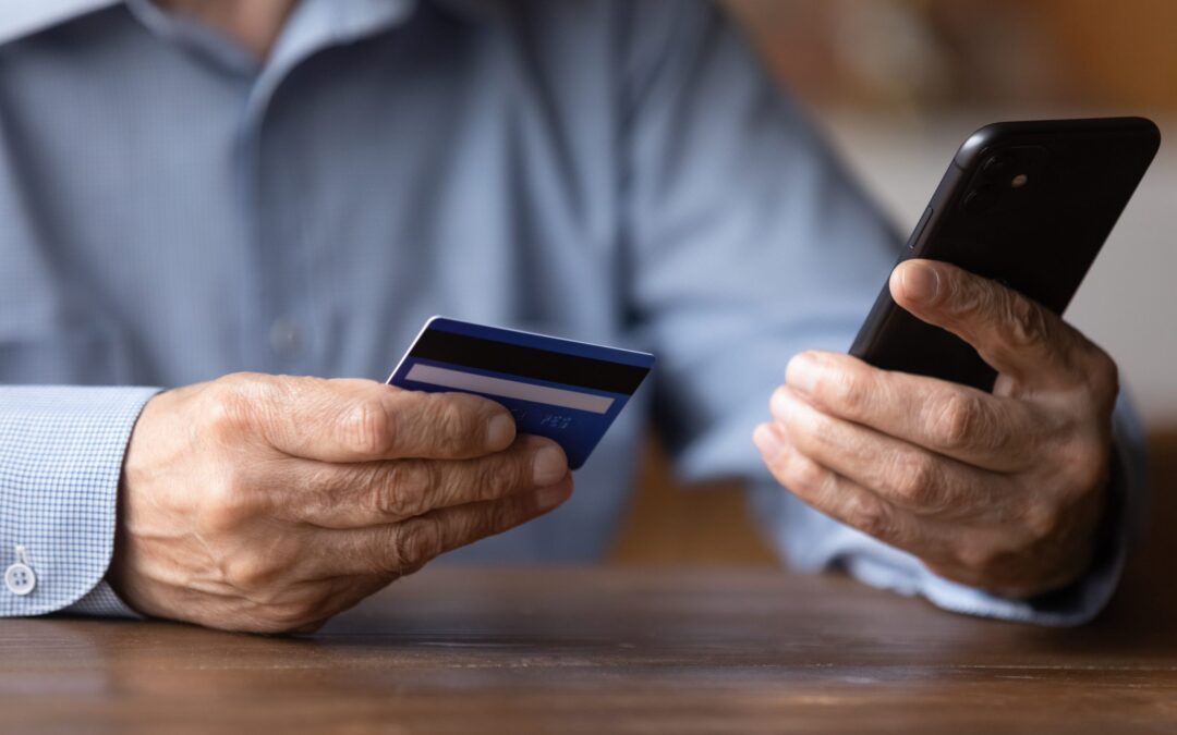 Close up senior man holding phone and credit card, shopping