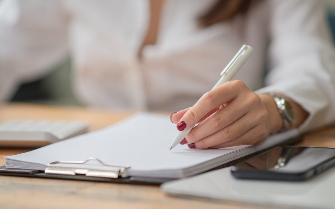 female hands with pen writing on notebook.